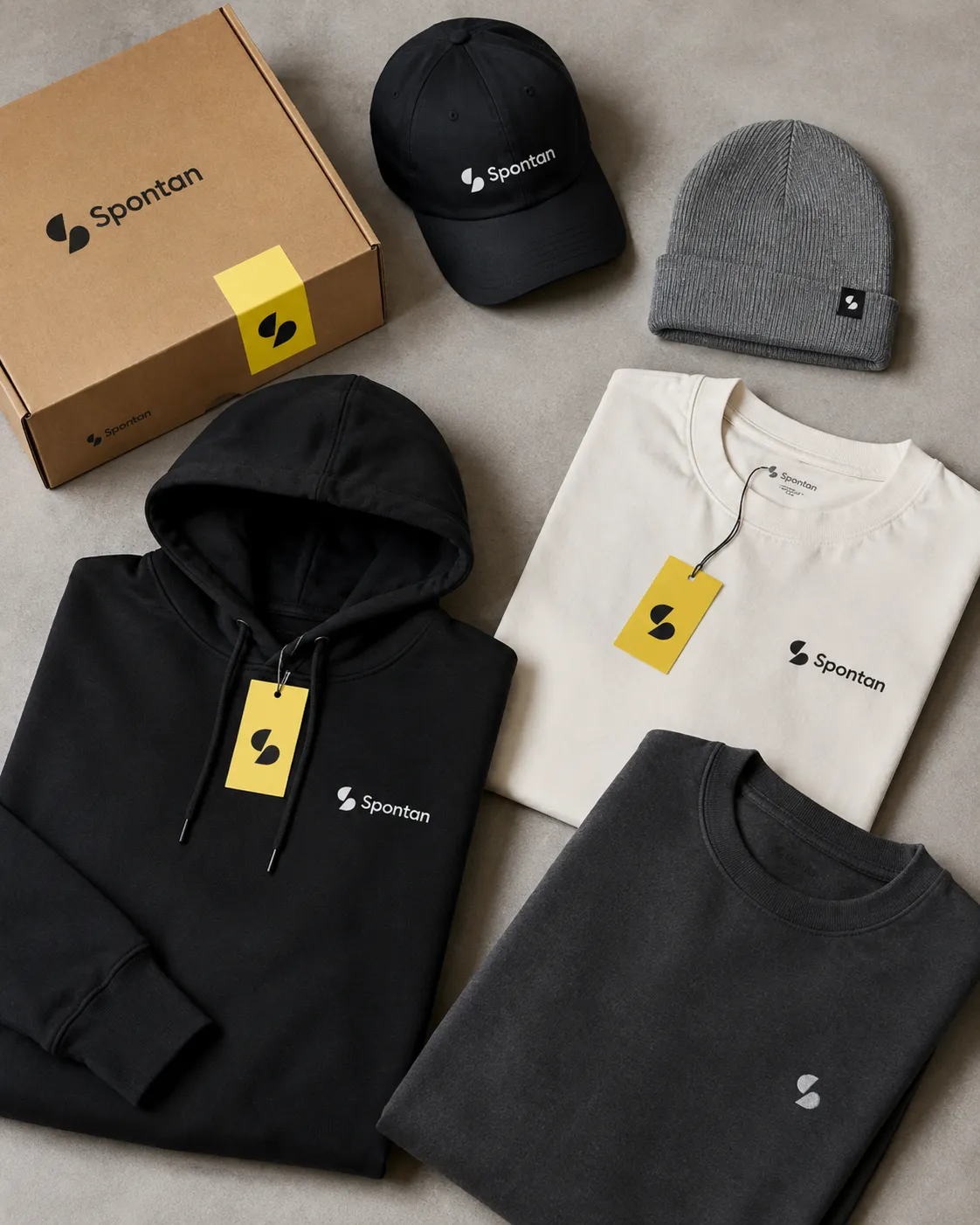 Spontan merch flat-lay: shipping box, cap, beanie, hoodie, tee and sweatshirt with yellow swing tags
