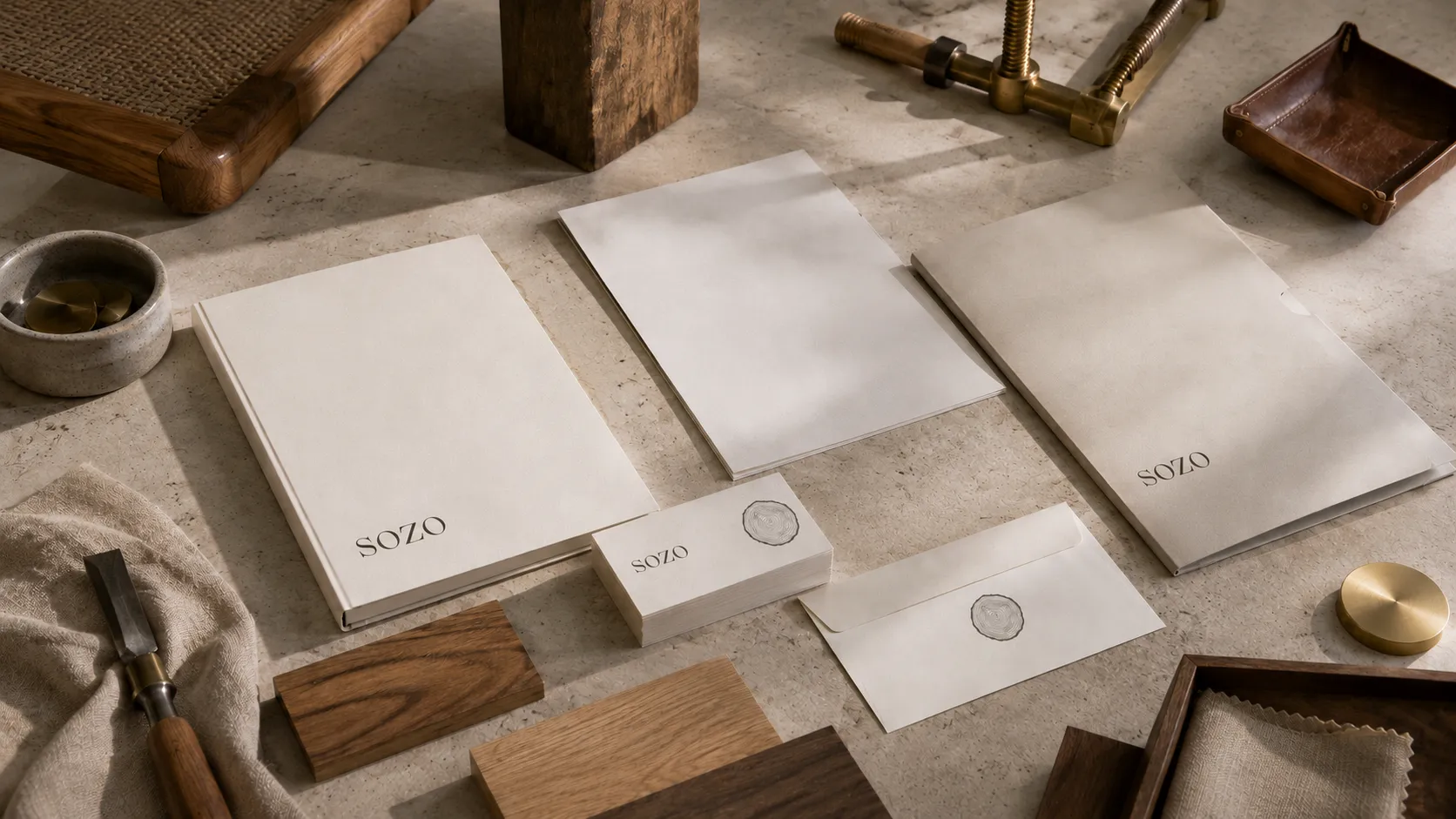 The SOZO identity applied across a book, letterhead, sealed cards and a folder