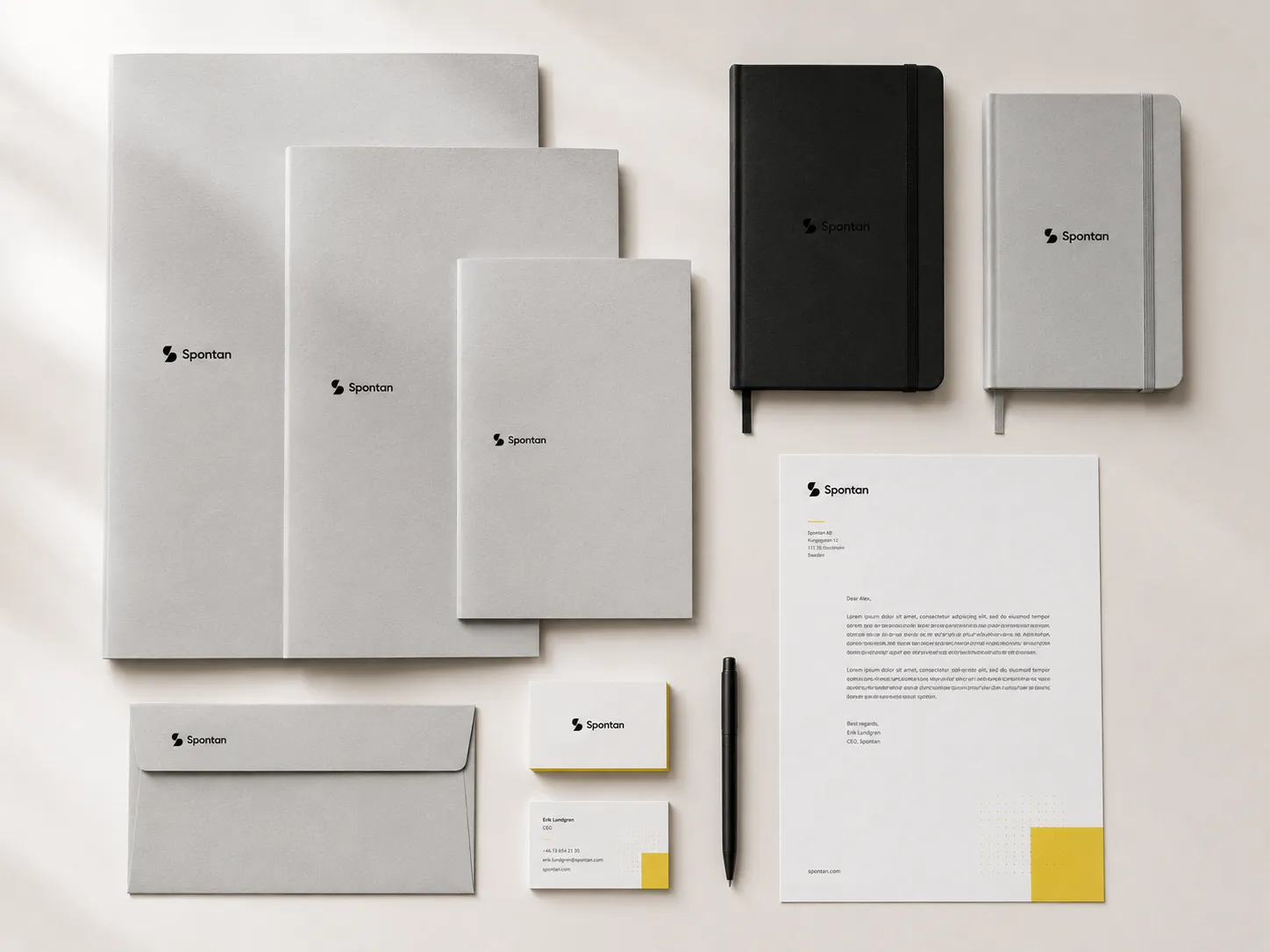 Spontan stationery laid out from above: letterhead, business cards, folder, envelope, notebook and planner